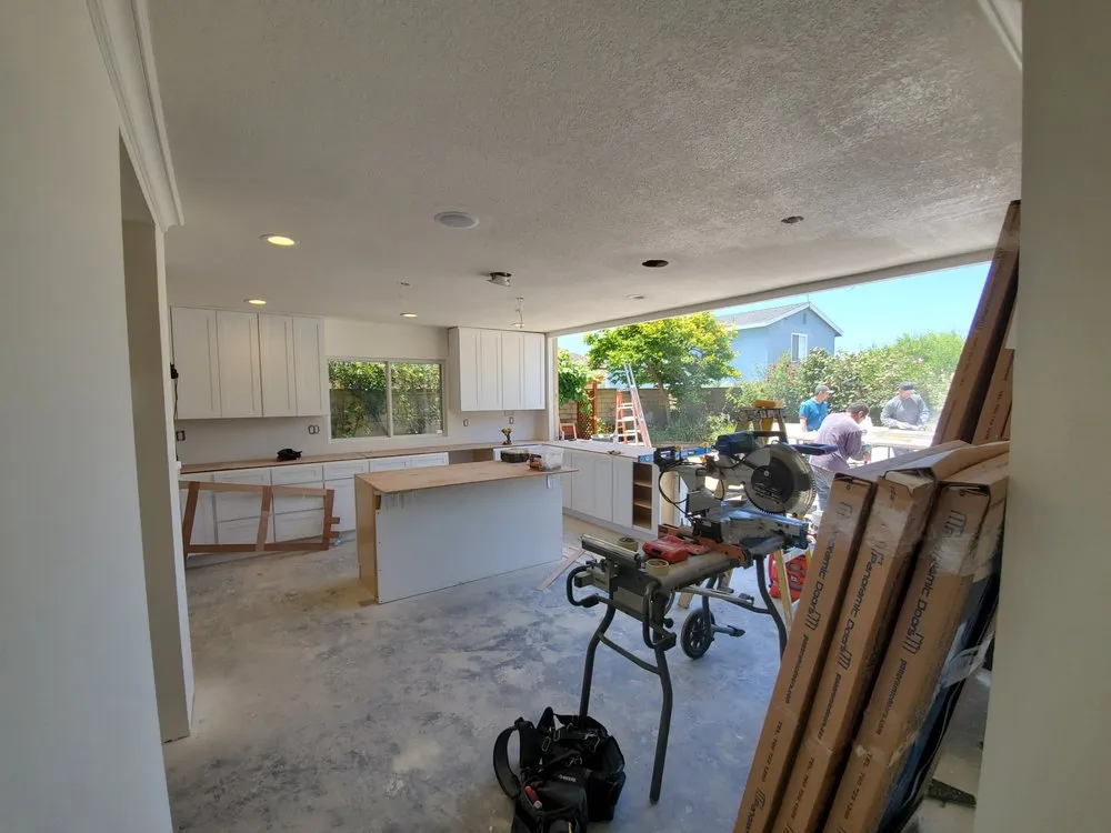 Kitchen mid-remodel with new cabinets being set against a freshly painted wall.
